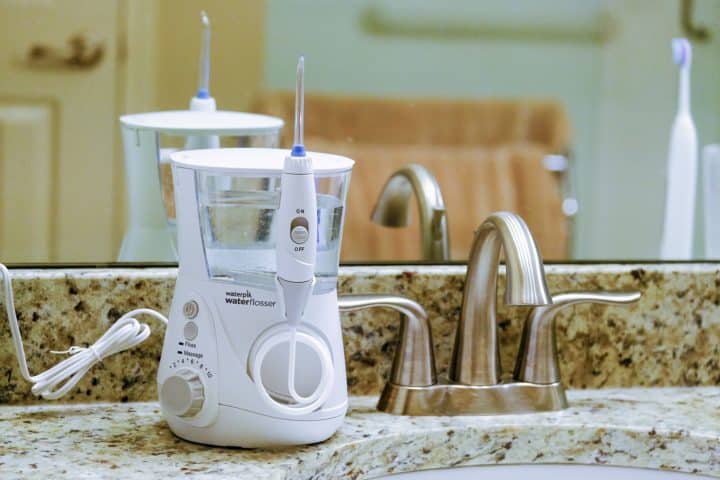 Waterpik water flosser on bathroom sink with mirror in the background