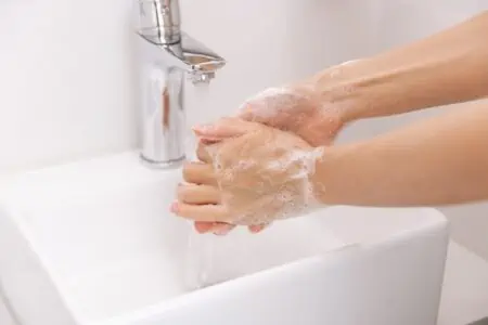 Female washing hands with soap under the flowing water tap