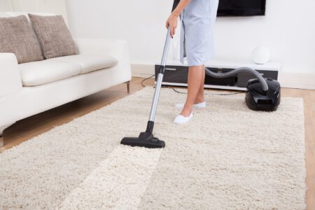 Female cleaning carpet in the living room with vacuum