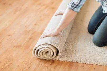 male hands unrolling carpet on wooden flooring
