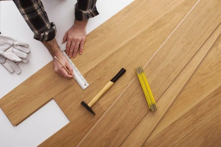Man installing wooden flooring and measuring with a precision ruler