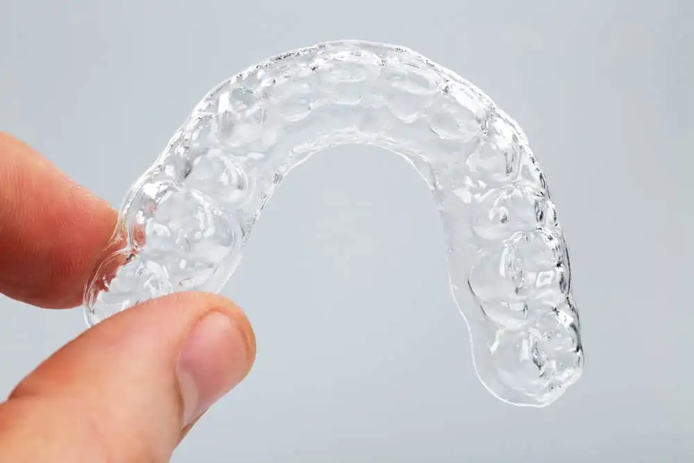 Hand holding clear plastic retainer