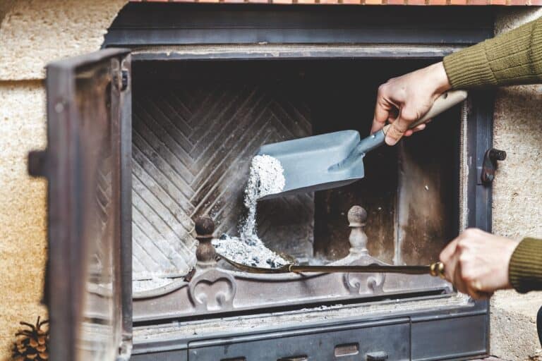 Male hand cleaning ashes in the fireplace