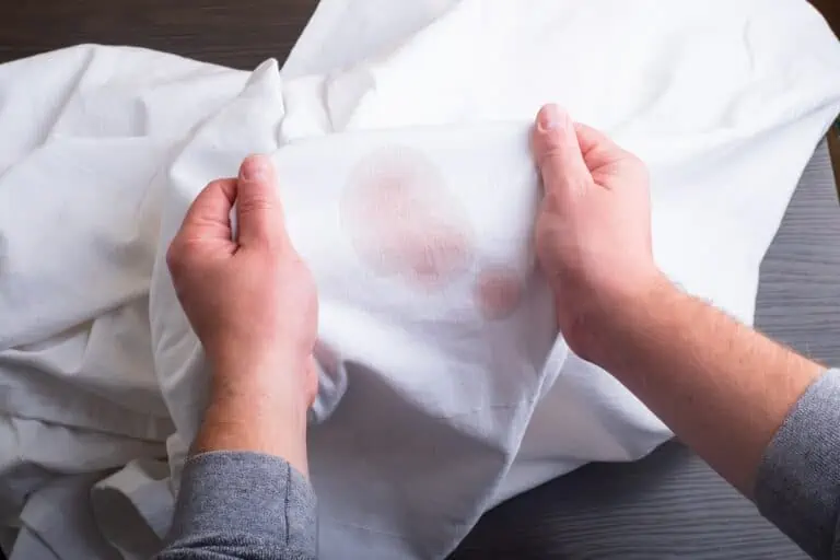 Man holding white shirt with stain from wine