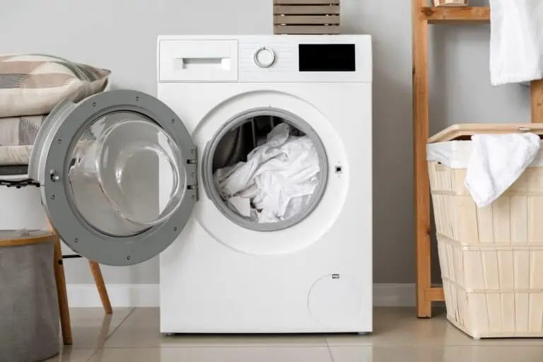 Modern washing machine with laundry in bathroom