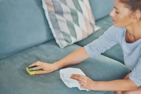 Woman cleaning sofa fabric with sponge