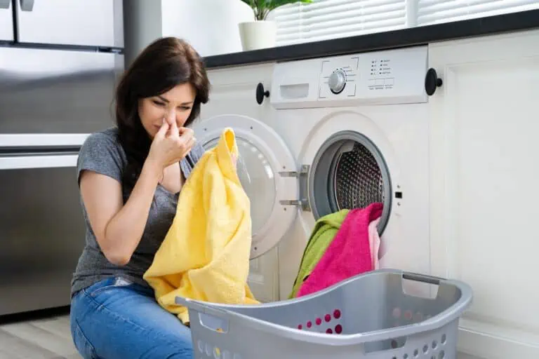 Woman looking at smelly clothes out of washing machine