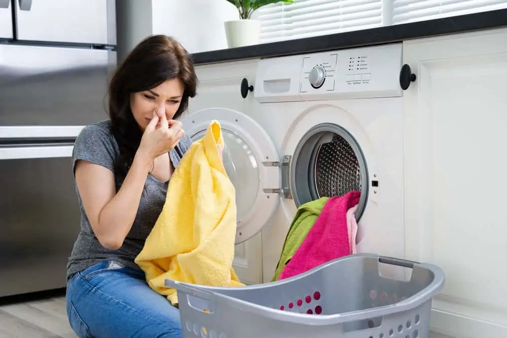 Woman looking at smelly clothes out of washing machine