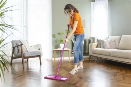 Housewife cleaning wooden laminate floor using microfiber mop pad