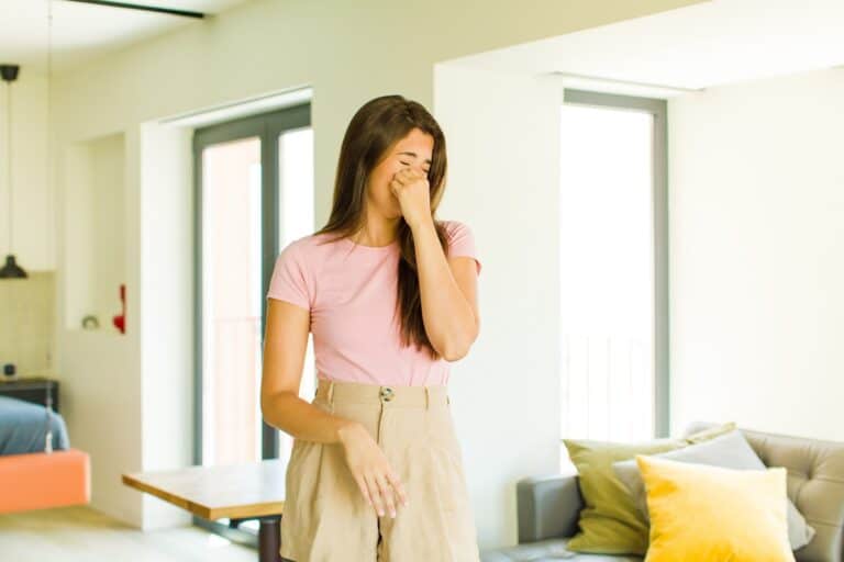 Woman holding nose to avoid smelling the unpleasant smell of the house